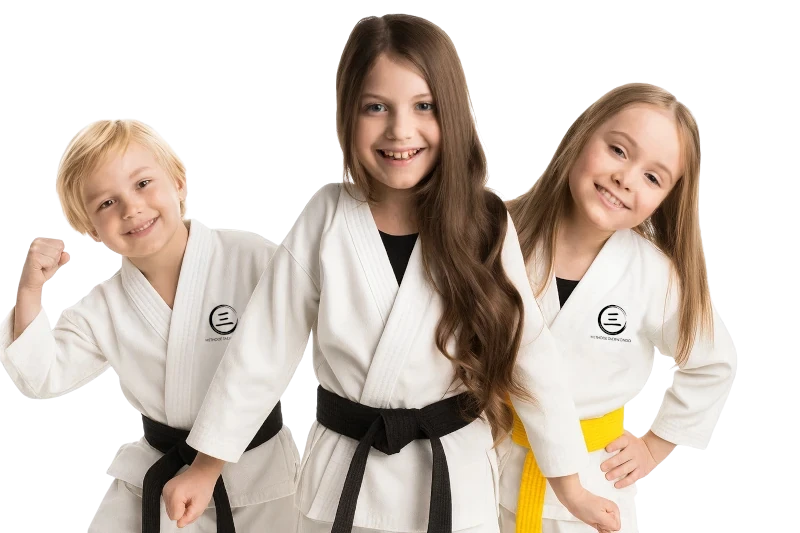 Drei Kinder in Karateanzügen mit farbigen Gürteln lächeln selbstbewusst in die Kamera.