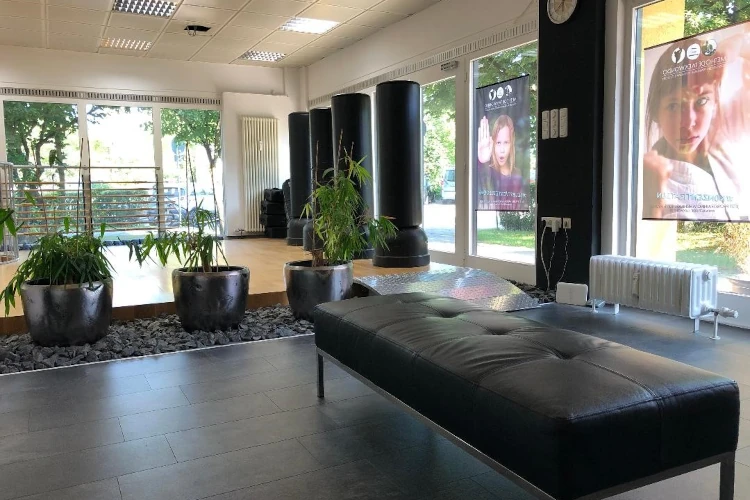 Moderner Kampfsport-Trainingsraum mit großen Fenstern, Sitzbank und Trainingsgeräten.